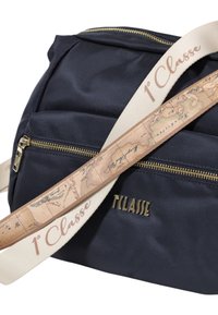Borsa in tessuto blu navy con zip dorate, dotata di una tracolla beige con stampa mappa e testo "1° Classe" in oro. Superficie texturizzata e design moderno.
