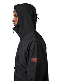 Seitenansicht einer Person, die eine schwarze Kapuzenjacke mit Reißverschlusstasche und einem braunen Fleck am Ärmel trägt.