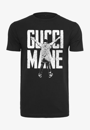 Mustvalge puuvillane T-särk, millel on graafiline trükk kujutisega laiali sirutatud kätega, tekst "GUCCI MANE" ja mustriga jersüdisain.