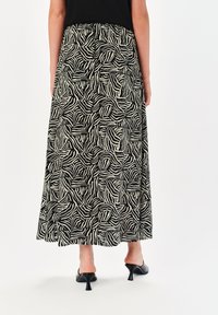 Spódnica maxi w czerni i kremie z wirującym wzorem zebry. Wykonana z lekkiego materiału, charakteryzuje się zwiewnym krojem i marszczoną talią.