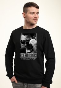 Felpa nera con stampa grafica di "Reservoir Dogs", con un'immagine in bianco e nero e testo bianco, che include una citazione e il titolo.