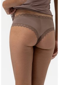 Braune nahtlose Panty mit gewelltem Spitzenrand. Weicher Stoff mit glatter Textur, designed für Komfort. Minimalistisch und diskret im Stil.