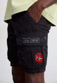 Black cargo shorts with a silver "AIR CREW" patch and colorful embroidered badge featuring a plane and "75th Fighter" text.