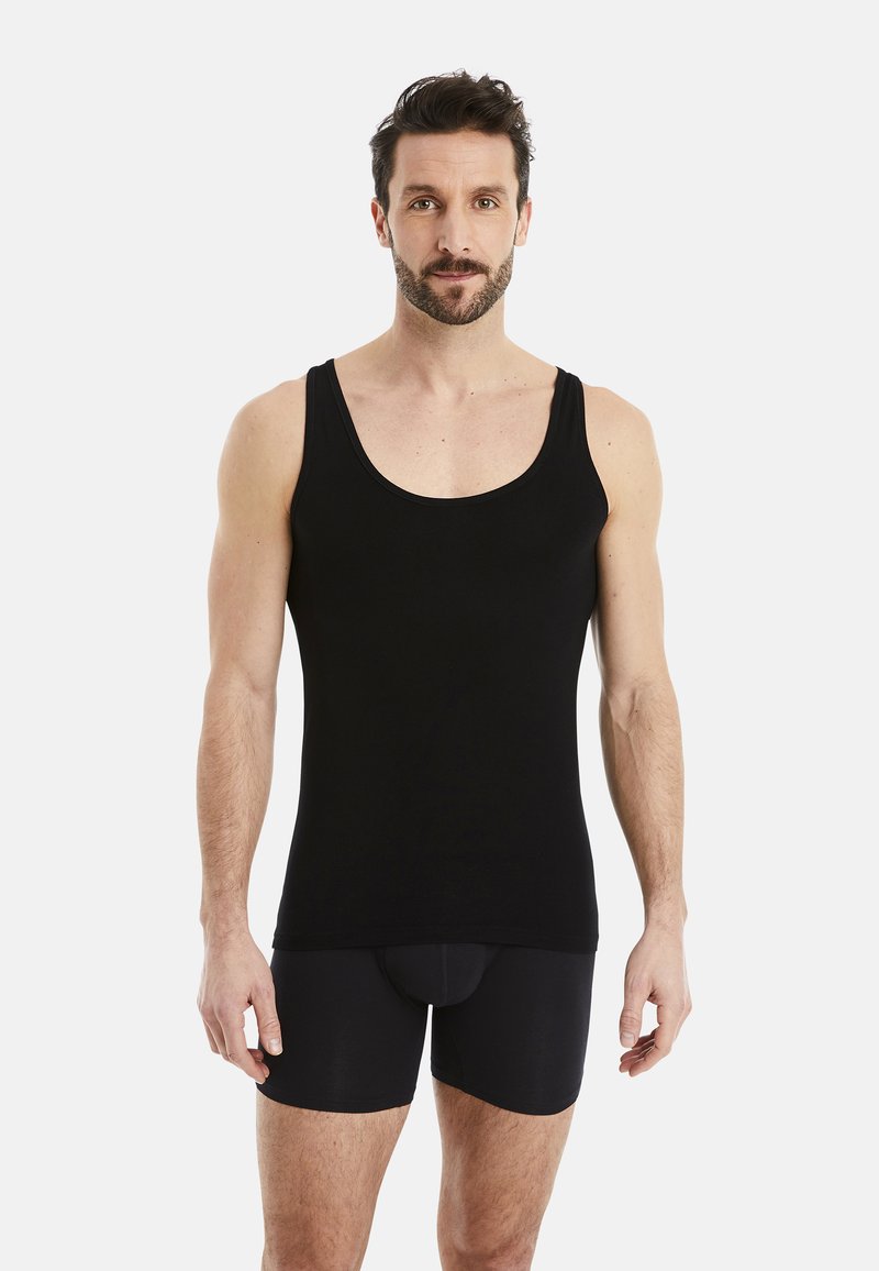 Black tank top made of soft fabric, featuring a rounded neckline and thick shoulder straps. Worn with black fitted shorts.