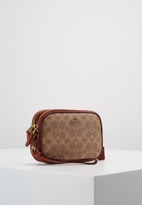 Sac bandouli ère en toile beige avec un motif répétitif de logo et des accents en cuir marron. Doté de ferrures dorées et d'une fermeture éclair.