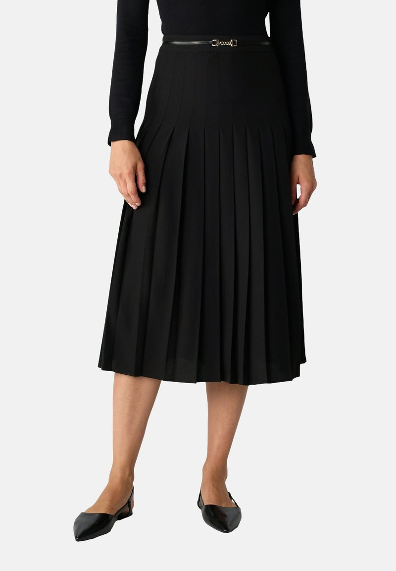 Gonna plissettata nera con vita aderente, dotata di una cintura nera slim con accessori metallici. Il tessuto strutturato aggiunge profondità e forma.