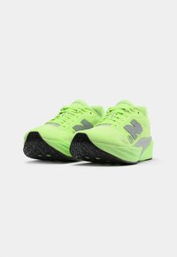 Lime green running shoes with a textured mesh upper, reflective accents, and a black patterned outsole for traction. Sleek, modern design.