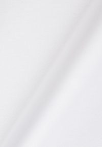 Tissu blanc lisse avec un pli diagonal subtil créant des ombres douces et une texture délicate à la lumière naturelle.