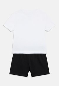 Λευκό βαμβακερό T-shirt με κοντά μανίκια, συνδυασμένο με μαύρο βαμβακερό σορτς. Απλός σχεδιασμός με στρογγυλή λαιμόκοψη και ελαστική μέση στο σορτς.