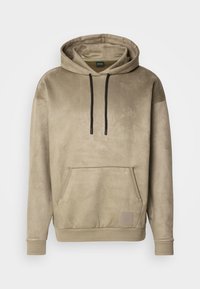 Sweat à capuche beige avec poche kangourou à l'avant, cordons noirs et petit patch carré sur la poche, présenté sur fond blanc.