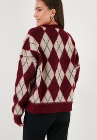 Bordeaux wolmix trui met een ruitpatroon in crème en grijs, met een relaxte pasvorm en een geribde onderrand en mouwen.