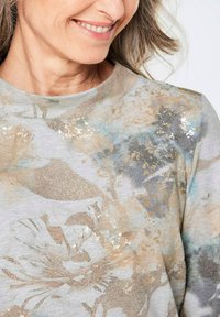 Lichtgrijze sweatshirt met een bloemenpatroon in beige, goud en zachte blauwtinten; ronde halslijn en zachte textuur.