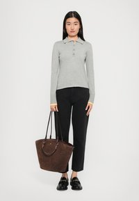 Gray long-sleeve polo with yellow accents, black jeans, and a dark brown tote bag with handles, worn with black loafers.