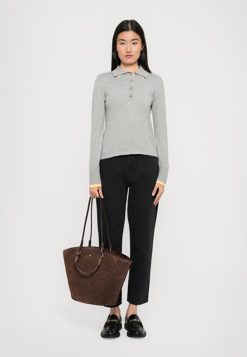 Gray long-sleeve polo with yellow accents, black jeans, and a dark brown tote bag with handles, worn with black loafers.