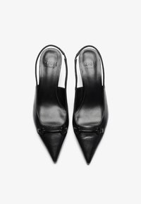 Mustat nahka slingback-korkokengät, joissa on teräväkärkiset varpaat, minimalisitinen muotoilu ja pieni koristeellinen yksityiskohta varpaien kohdalla.