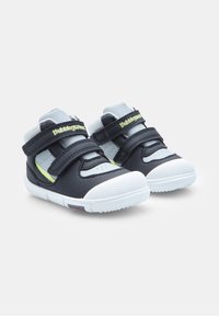 Scarpe sintetiche nere con dettagli grigi chiari, suola in gomma bianca e due cinturini in velcro regolabili. Punta arrotondata e suola texturizzata.