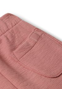 Nahaufnahme von staubigen rosa Stoffhosen mit einem elastischen Bund und einem rechteckigen Patch, der nahe einer Gürtelschlaufe genäht ist.