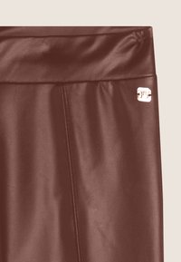 Pantaloni finti in pelle rossa con una texture liscia, dotati di una cintura alta e un piccolo logo metallico sul lato.