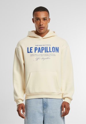 Sudadera crema con bolsillo canguro, que presenta un texto azul en negrita. Corte holgado con puños y dobladillo acanalados. Textura suave, diseño simple.