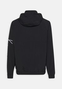 Chaqueta con capucha negra hecha de material ligero. Presenta puños y dobladillo elásticos, con un diseño de acento blanco en la manga.