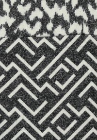 Stickad tyg med två mönster: toppen i grå och vit abstrakt design; botten har ett geometriskt zigzag-mönster i svart och vitt.