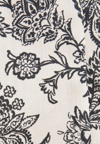 Tissu blanc avec des motifs floraux et feuillage noirs complexes, comportant des dessins détaillés, symétriques et des formes florales variées.