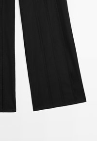 Zwarte wijde broek met een gladde textuur, voorzien van verticale naden en een nette afwerking, ontworpen voor een ontspannen pasvorm.