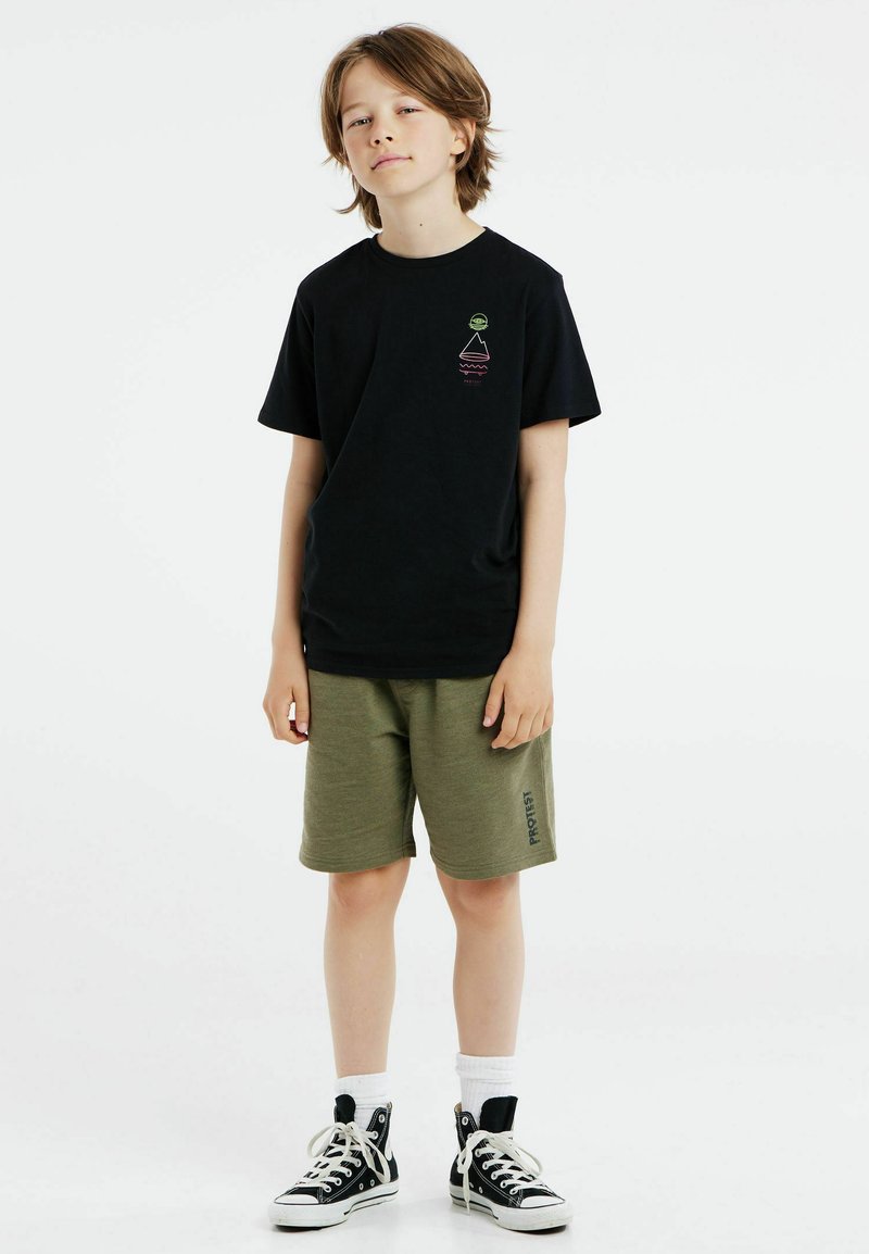 Schwarzes Baumwoll-T-Shirt mit einem kleinen Grafikmotiv auf der Brust, kombiniert mit olivgrünen Shorts und schwarzen Sneakers. Weiße Socken sind sichtbar.
