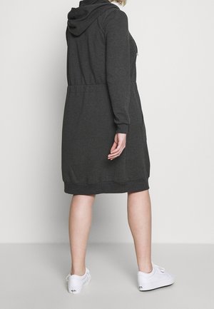 Dressing med hætte i kulgrå, langærmet sweatshirtdragt med taljesyning, to sidelommer samt ribkanter ved ærmer og kant. Kombineret med hvide sko.