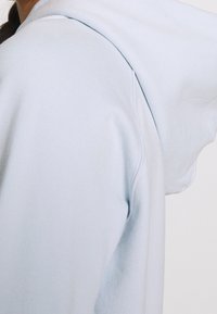 Sudadera azul claro con capucha, textura suave, costuras acanaladas y un corte oversize con diseño de hombros relajado.