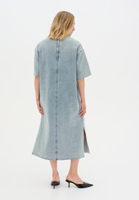 Heledest sinine denim midi kleit lühikeste varrukatega, keskel tagaõmblus, külgmised lõhed ja hõõrdunud ääred. Kandmiseks mustad kõrged tõstukid.