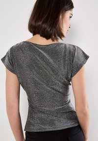 Kurzarmoberteil aus metallic schwarzem Stoff mit glänzender Textur, mit einem drapierten Rückendesign und einer taillierten Silhouette.