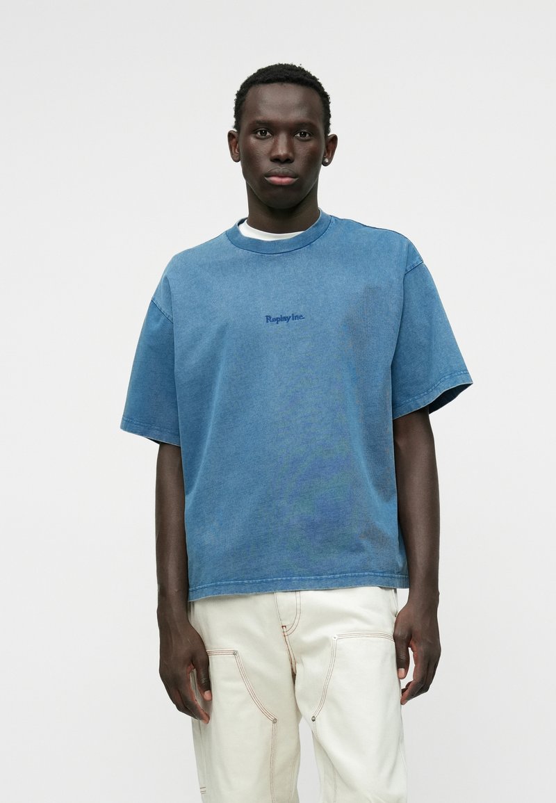 Τζιν πουκάμισο κοντομάνικο σε ανοιχτό μπλε, με ριμπ λαιμόκοψη και κεντημένο λογότυπο 'Replay Inc.' σε σκουρότερο μπλε. Άνετη εφαρμογή.