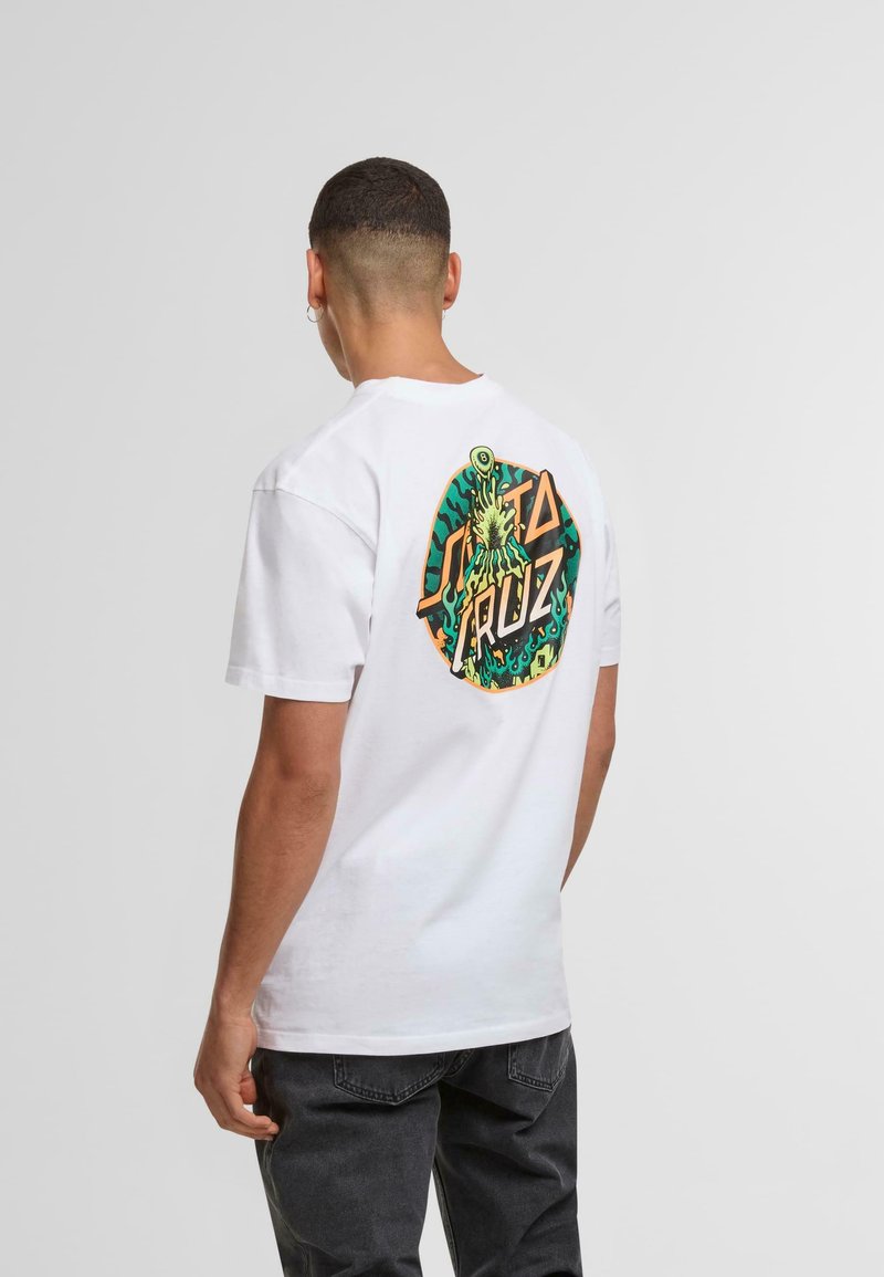 Bílý bavlněný tričko s kulatým potiskem na zadní straně, které obsahuje zelené a oranžové vzory, text "Santa Cruz" a abstraktní motivy.
