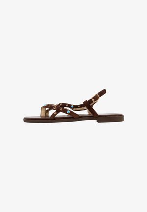 Sandale plate marron avec plusieurs brides ornées de clous bleus et dorés et une bride de cheville réglable avec boucle dorée.