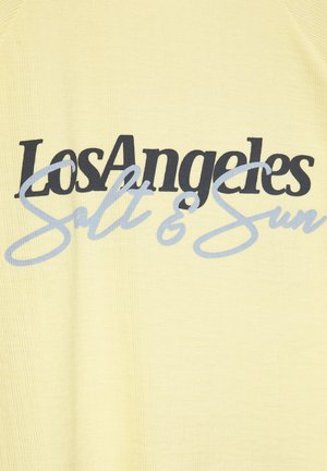Tissu jaune avec texte noir en gras "Los Angeles" superposé d'un texte cursif bleu clair "Salt & Sun" sur un vêtement.