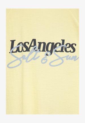 Tissu jaune avec texte noir en gras "Los Angeles" superposé d'un texte cursif bleu clair "Salt & Sun" sur un vêtement.