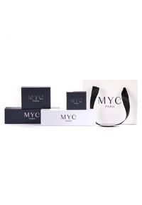 Il set di imballaggio Myc Paris include scatole nere e bianche di diverse dimensioni con loghi in rilievo e una borsa bianca con manici neri.