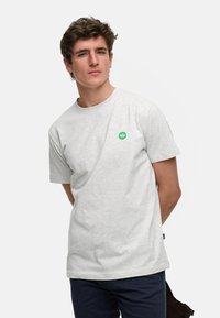 Lys grå bomulls t-skjorte med rund hals, korte ermer og en liten grønn logo på brystet. Glatt tekstur med en avslappet passform.