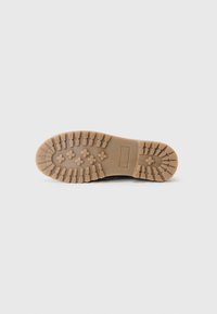 Rubber outsole with a textured, grip pattern featuring hexagonal and circular shapes in beige. Flat design suitable for versatile use.