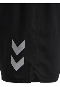 Svarta sportshorts med en elegant design, tillverkade av mjukt material, med tre silverfärgade chevronmönster på vänster sida nära fållen.