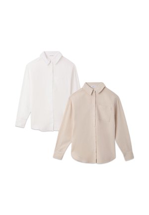 Camicia button-up beige chiaro con maniche lunghe, abbinata a leggings neri e sneaker argentati. Tessuto liscio e vestibilità rilassata.