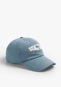Blå bomuldsberet med hvid broderet tekst og grønne detaljer, buet skygge og seks ventilationshuller. Enkel, ustruktureret design.