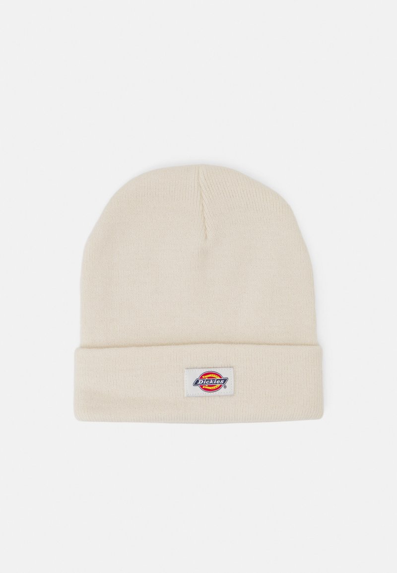 Cream knit beanie with a folded cuff and a rectangular label featuring a multi-colored logo. Soft texture and classic design.