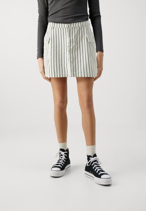 Jupe mini rayée en tissu léger avec une taille solide, dotée de deux poches latérales et d'une fermeture à boutons, associée à des baskets montantes noires.