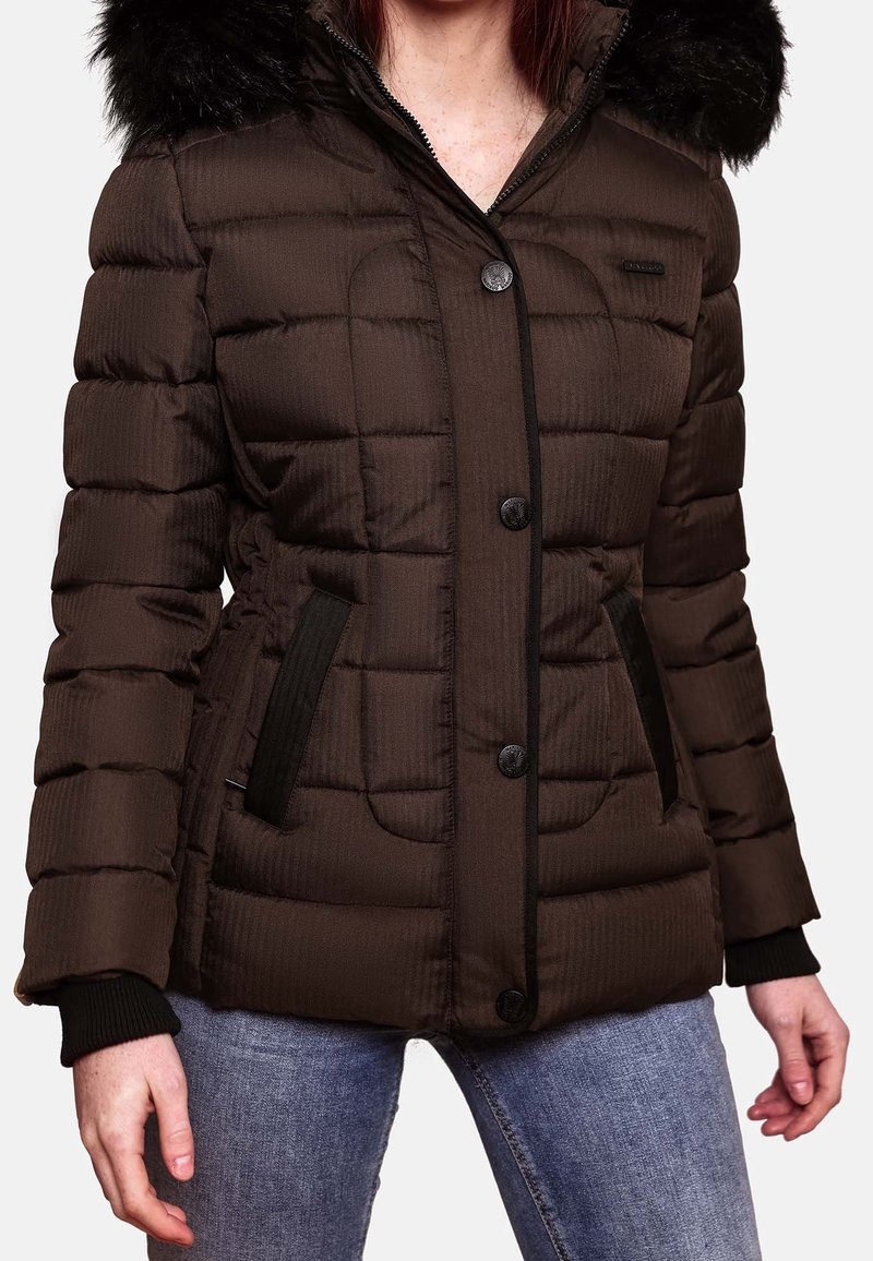 Femme portant une veste d'hiver matelassée marron foncé avec une capuche en fourrure noire et des boutons noirs, associée à un jean bleu.