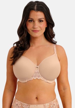 Sujetador beige con copas lisas, detalles de encaje floral en el centro y las tiras, y un pequeño lazo en la parte delantera. Textura de tela suave.
