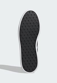 Suela de zapatilla negra con un patrón de diamante, que presenta un borde blanco, textura suave y forma redondeada.