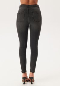 Svart jeans med hög midja, femficksdesign och synliga sömDetaljer. Slät textur och avsmalnande ben.