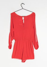 Tutina rossa con maniche lunghe, dotata di un'apertura a chiave sul retro, vita elastica e accenti ricamati bianchi sui polsini. Tessuto dalla finitura liscia.